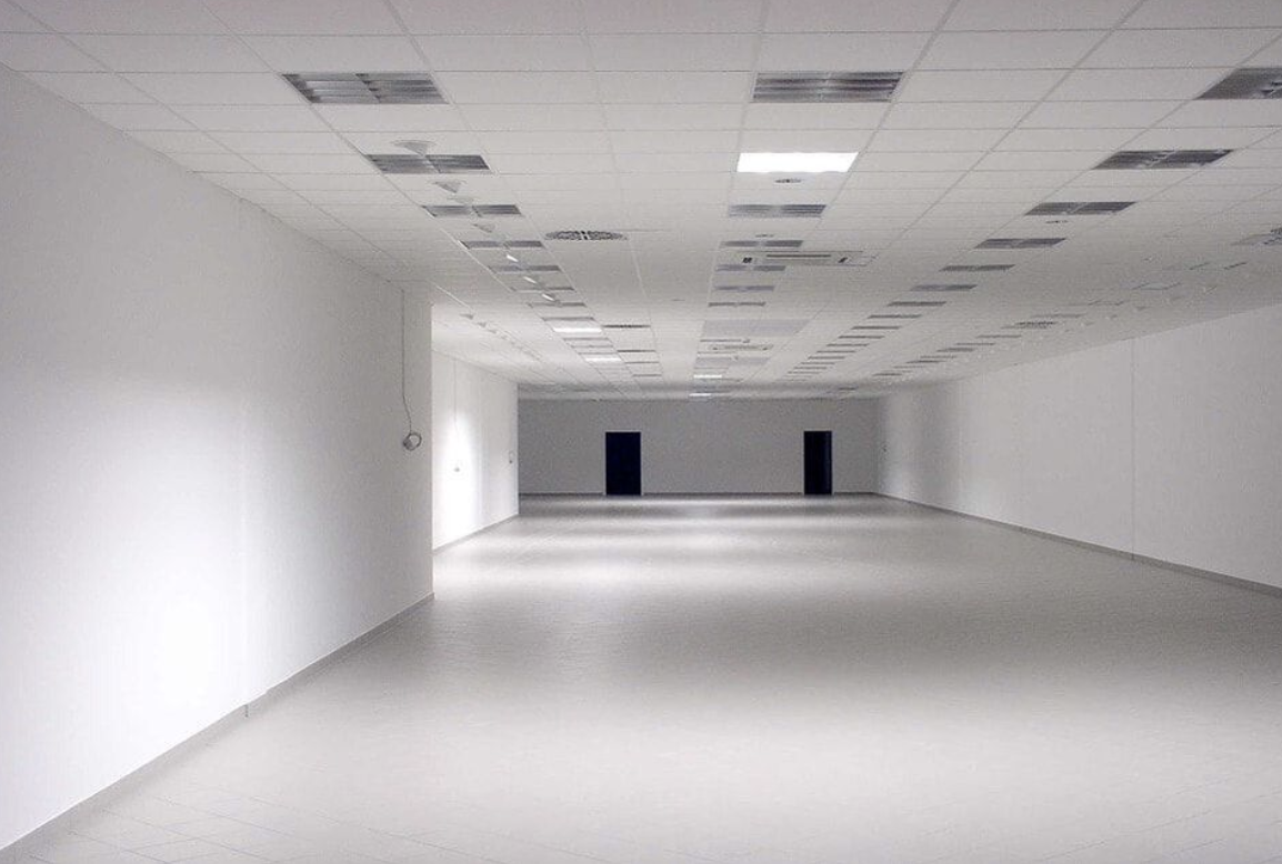 This picture is of a finished empty office floor. The walls and floor are perfectly finished, and there is really harsh industry lighting and tiled ceilings. 